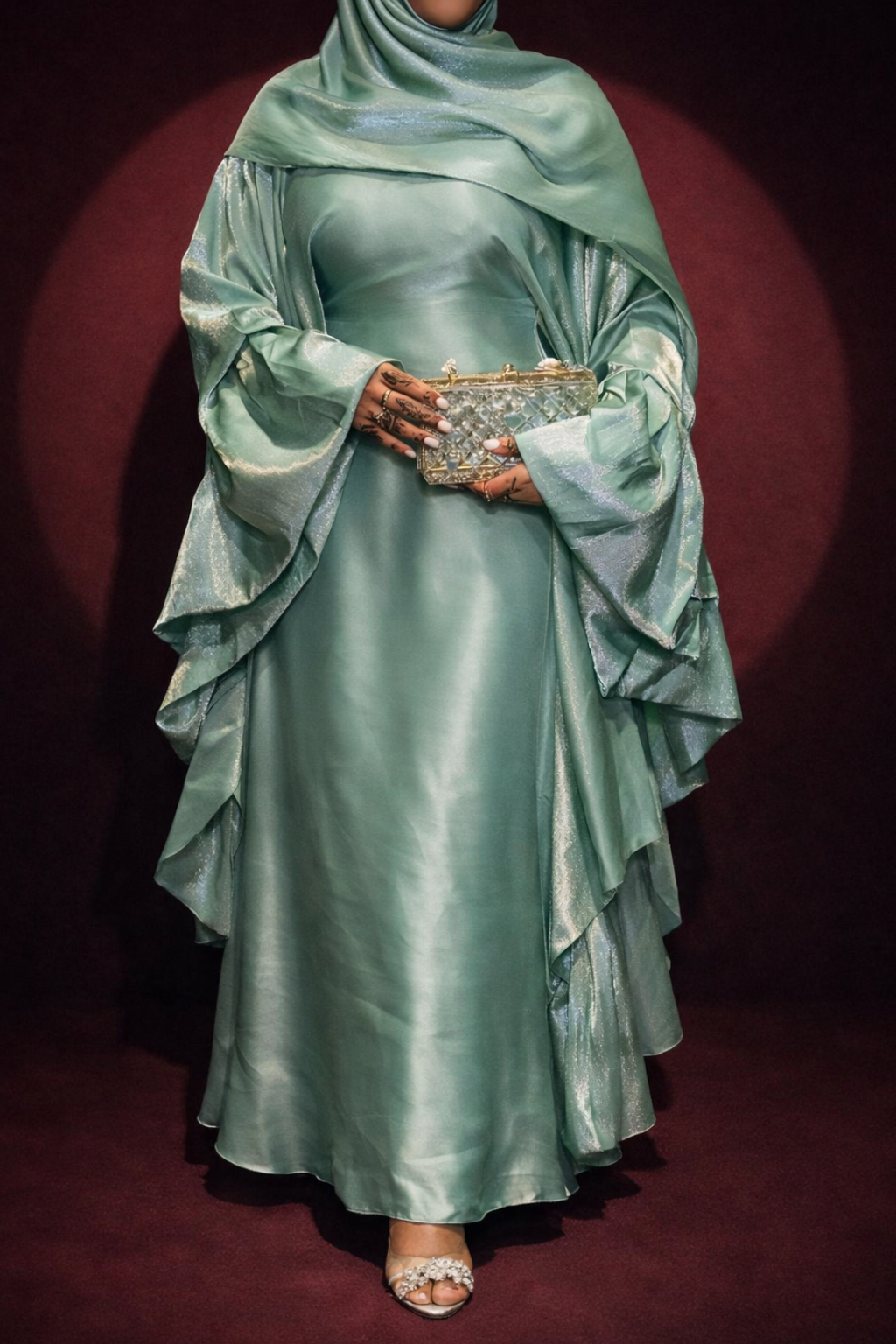 Person wearing a light green formal gown with a matching headscarf on a dark background